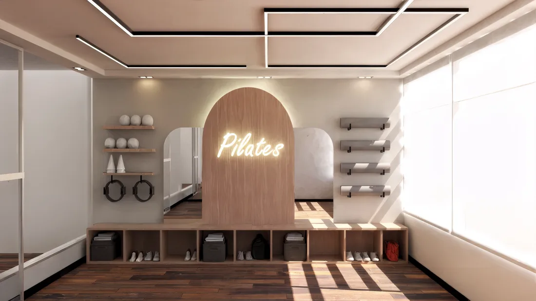 Salón de pilates con arco iluminado, letrero de neón y equipamiento en madera